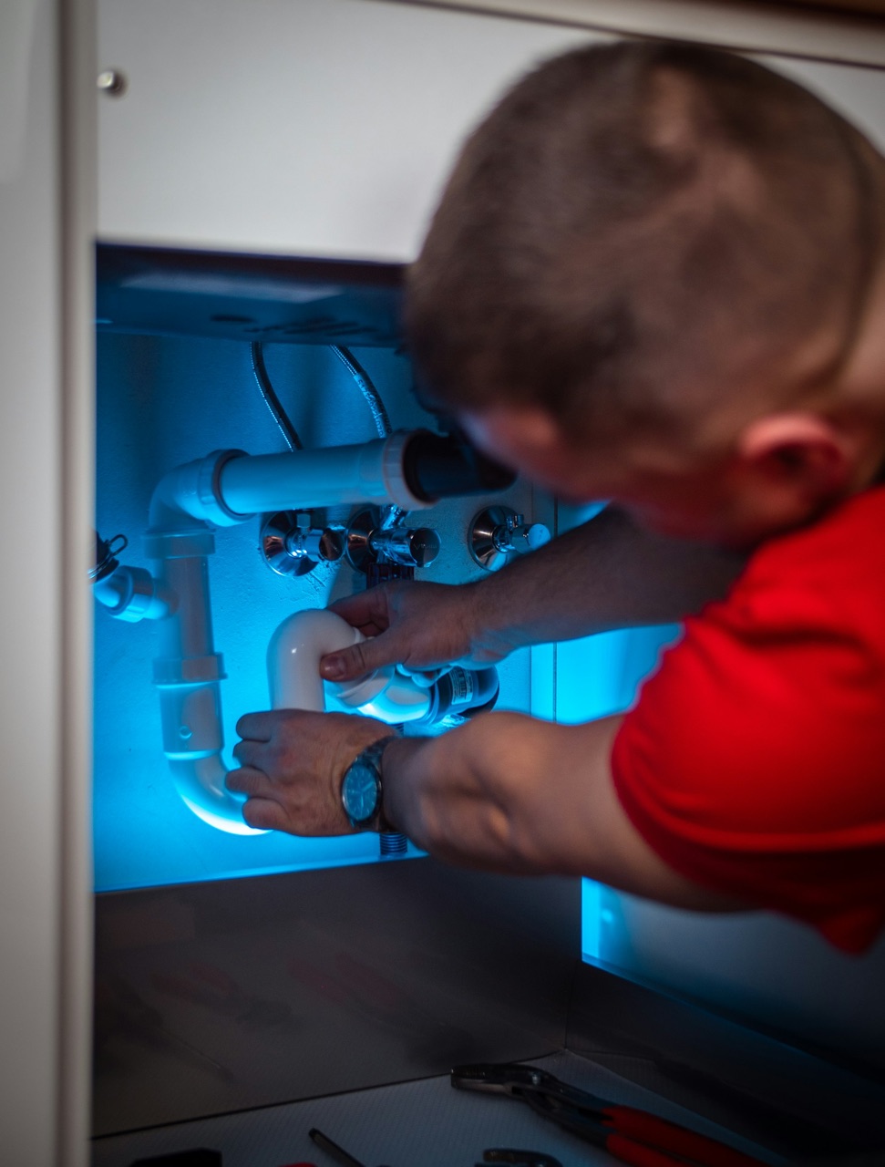 Plumber repairing pipes under a residential kitchen sink